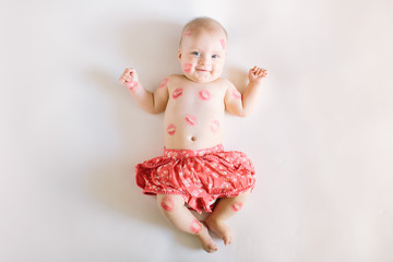 Image of adorable child with red kisses on the skin, happy baby girl isolated on white background,...
