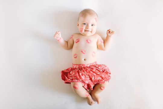 Image of adorable child with red kisses on the skin, happy baby boy sitting down in the studio and isolated on white background, little love angel, romantic holiday, Valentines day concept