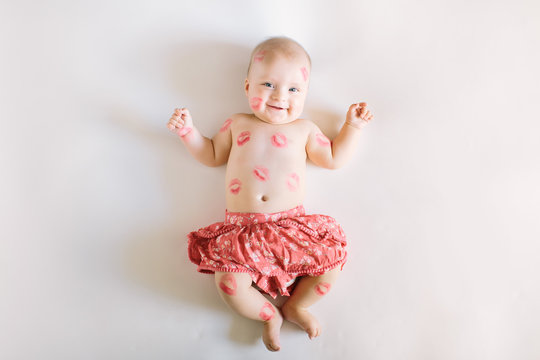 Image of adorable child with red kisses on the skin, happy baby girl isolated on white background, little love angel, romantic holiday, Valentines day concept