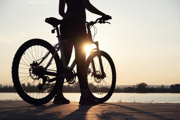 Naklejka na ściany i meble Silhouette of a girl near sea on the bike. Sport and active life concept