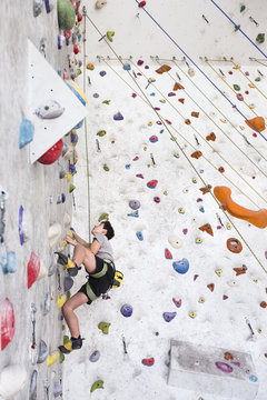 Young rock climber training on an indoor climbing wall