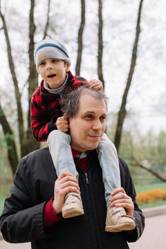 Father carry his son with infant cerebral paralysis on shoulders