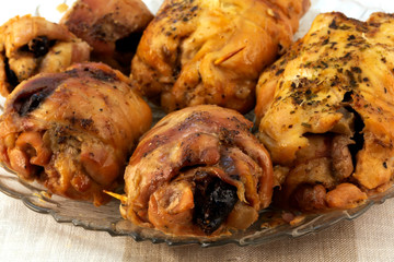Cooked meat rolls with dried prunes with baked crust on a glass plate.