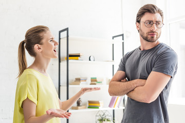 side view of woman yelling at boyfriend while she standing with crossed hands