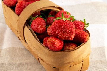 A woven basket made of bast, filled with large juicy strawberries.