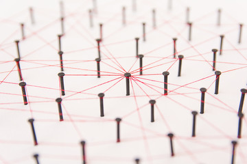 Linking entities, social media, Communications Network, The connection between the two networks. Network simulation on white paper linked together created by black nail and red thread