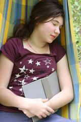 introvert teenager girl napping with book in hammock on summer outdoor green garden background