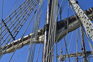 Vintage tall ship mast and rope rigging, blue sky