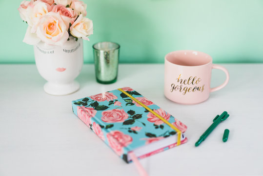 Feminine desk with notebook, coffee, and flowers