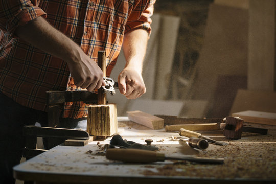 Young carpenter working with cabinet scrapper in his workshop