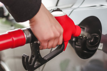 Man hand is inserting a fuel nozzle in a gas tank. Car gas station. Refueling concept.
