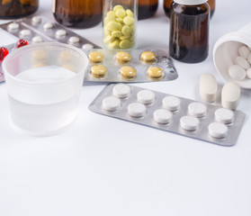 Tablets and a glass with water on a background of medical preparations. Medical concept