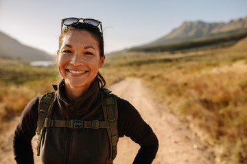 Smiling asian woman with backpack on country hike