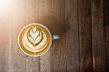 A white cup of coffee latte or cappuccino art on wood table