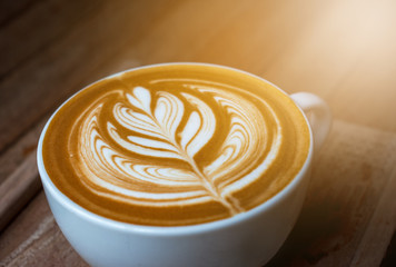 A white cup of coffee latte or cappuccino art on wood table