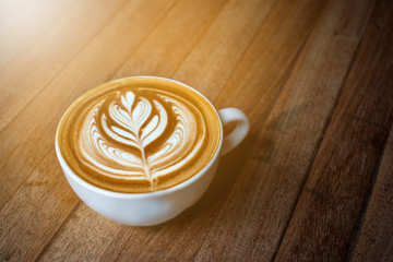 A white cup of coffee latte or cappuccino art on wood table