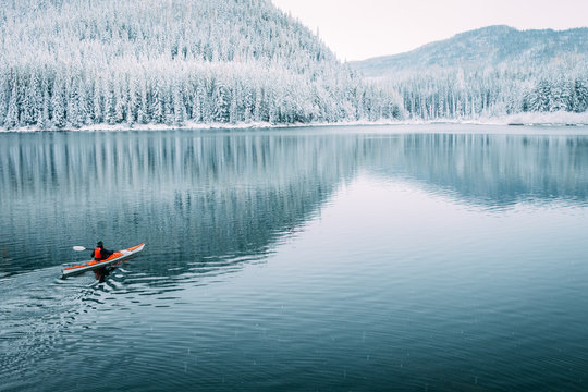 A solo kayaker paddles on a still lake one quiet winter morning in Montana