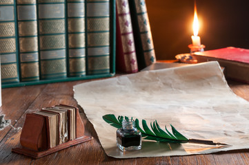 Quill pen and old paper with old books at candle light