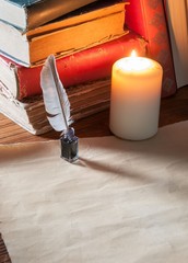 Quill pen and old paper with old books at candle light