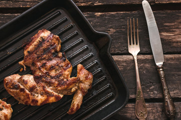 Grilled turkey meat on the pan on the wooden background.