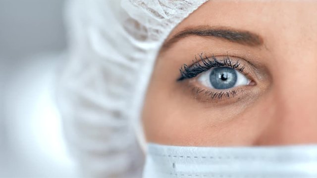Medical nurse or scientist in surgical mask on blurred background in a hospital or lab