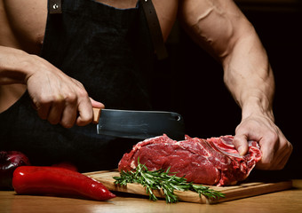 Strong sport man prepare cook beef steak ribs on dark kitchen background healthy eating concept on black 