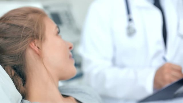 Doctor and nurse discussing with young woman patient in hospital