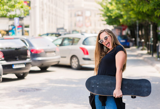 Smiling skater girl holding skateboard