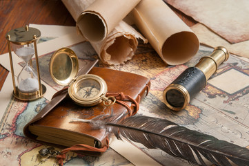 Quill pen and a notebook with old rolled papers, maps and vintage items