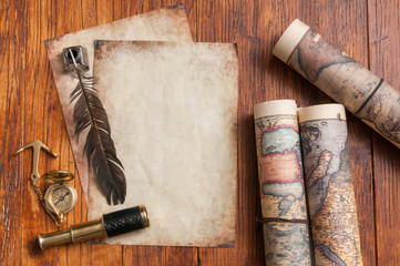 Quill pen on old paper sheets with old rolled maps and vintage items