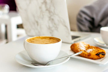 White Latte in Mug with Croissant At Coffee Shop Cafe Laptop Marble Woman Girl in Blurred Background Negative Space Copy Art Spoon Freelance Work Remotely