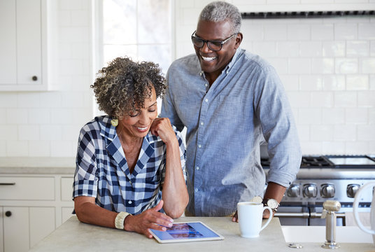 African American Senior Couple looking at cell phone in the kitchen together