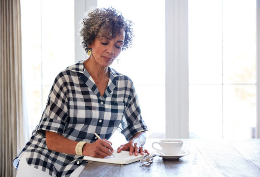 Senior African American Woman Drinking Tea And Writing In Her Journal