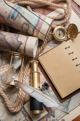 Quill pen and a notebook with old rolled papers, maps and vintage items