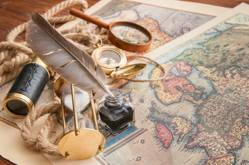 Quill pen and old papers on an old map with vintage items
