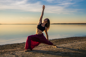 Fototapeta na wymiar Silhouette woman on the beach at sunset doing yoga asana. Morning natural stretch warm-up training