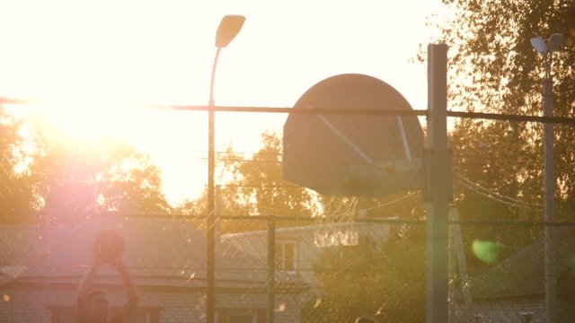 Basketball In The Sunset. Playing basketball at the sunset. The game of basketball on outdoor playground.