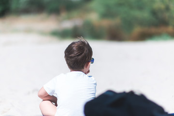 young caucasian kid sitting on beach sand