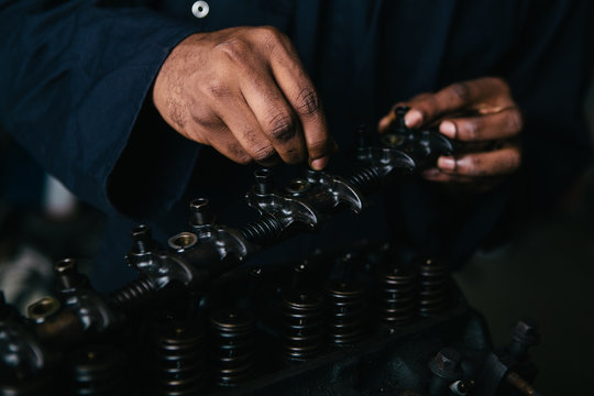 Mechanic fixing an engine for a head gasket repair in a garage.
