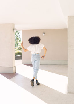 Back portrait of girl dancing in pastel background