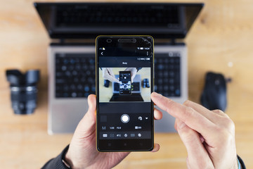 Smartphone in Hand and Laptop in Background Droste Effect