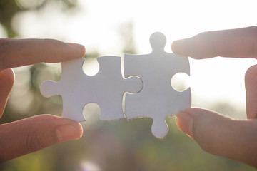Two-handed jigsaw puzzle piece connectors, green bokeh background, Joint Business Concepts