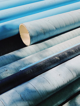 A pile of blue tubes stacked on top of each other for construction or plumbing.