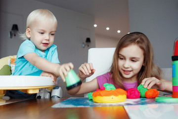 Fototapeta premium Two happy children Blond boy and girl playing sitting at table at home