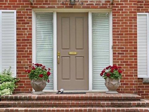 front door with newspaper and pots of geraniums