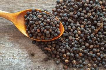 Top view black pepper corns on wooden background