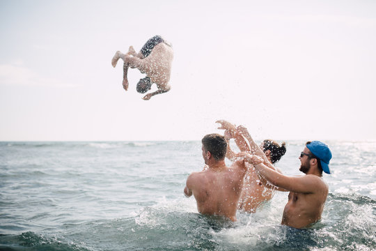 Group of friends throw their friend into water