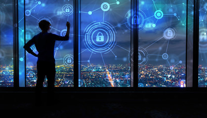Cyber Security with man writing on large windows high above a sprawling city at night