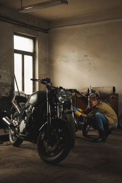 Young female working on restoration of old /vintage motorbikes in old rusty motorbike garage/workshop