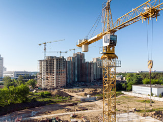Fototapeta na wymiar yellow tower crane on background of residential building construction